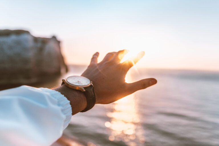Eine Männerhand vor einem Sonnenuntergang ausgestreckt als Metapher für eine 'Vision'
